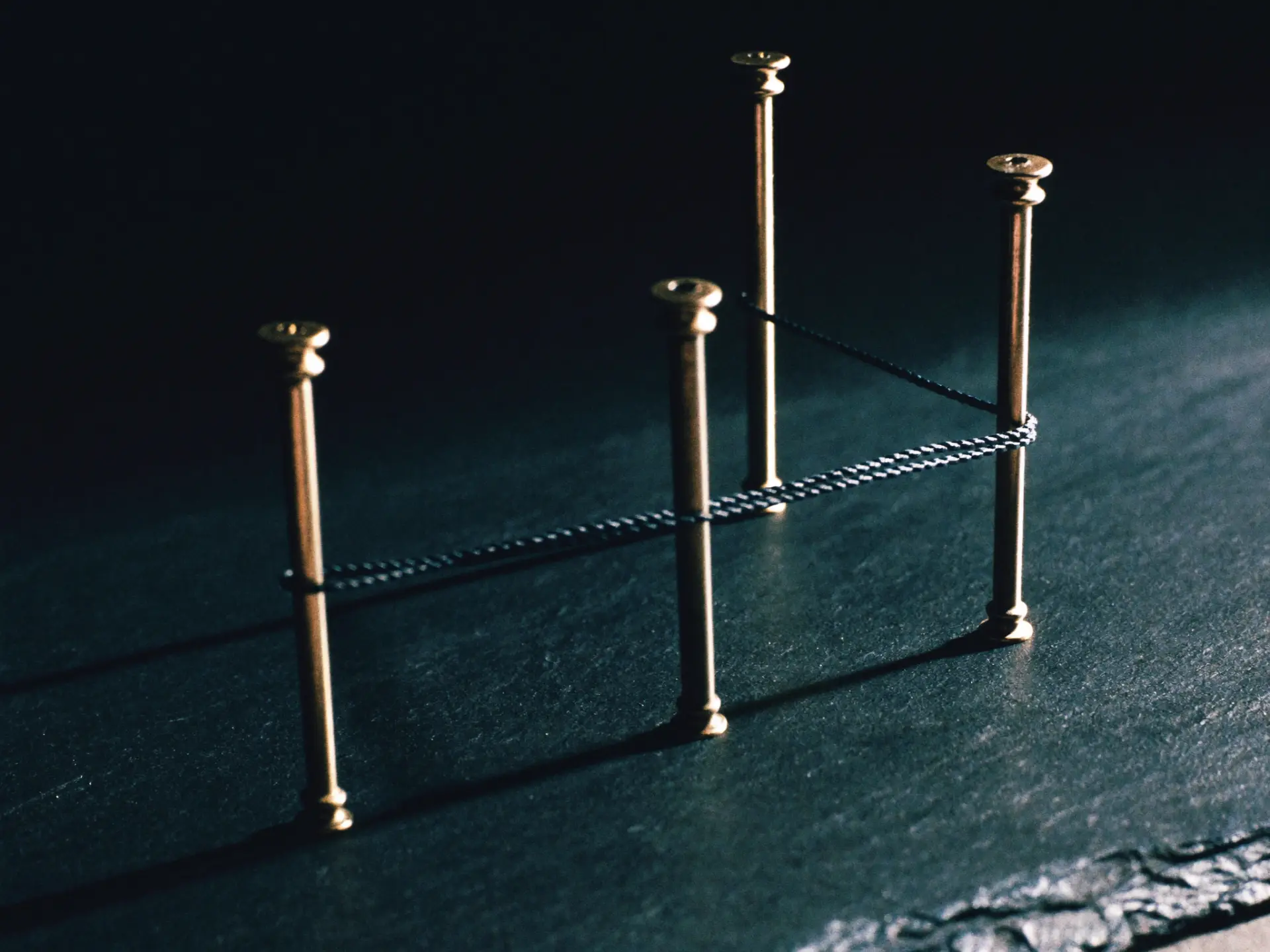 Four brass pins holding a single taut thread